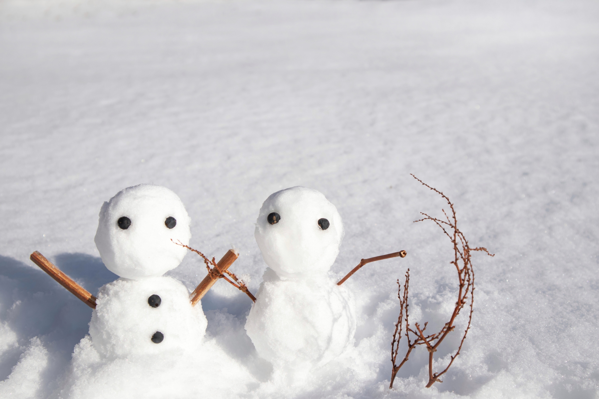 雪に覆われた地面に並ぶ雪だるまの写真。冬は濡れた雪や氷が電気を伝えやすく、落雷地点から離れた場所でも感電する側撃雷の危険性が高まることを解説するためのイメージ。
