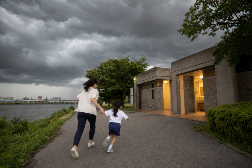 雷から避難するため河川公園の管理棟へ向かう親子