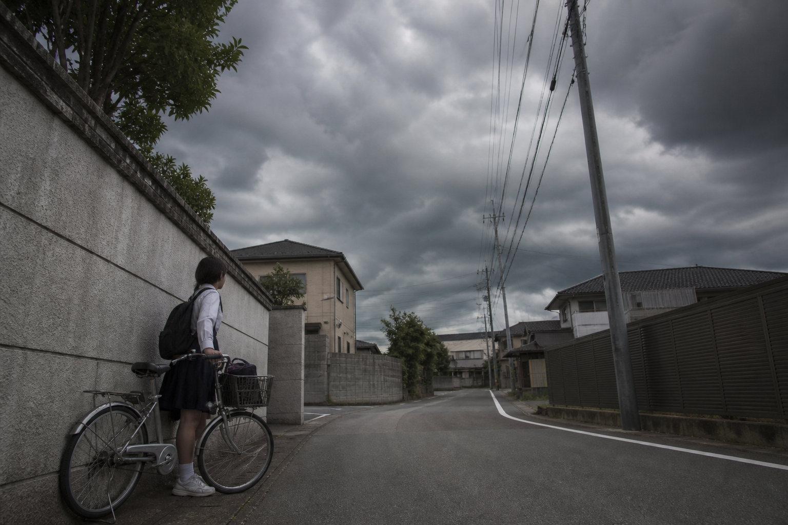 自転車を降りて建物の陰に避難する中学生