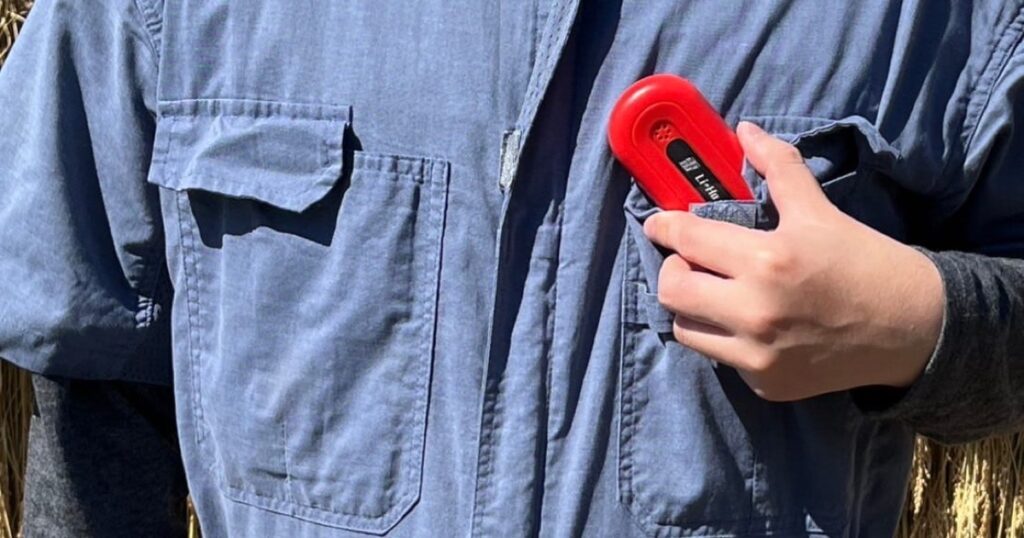 作業着の胸ポケットに、赤い雷検知器「雷報」を入れている農家の男性